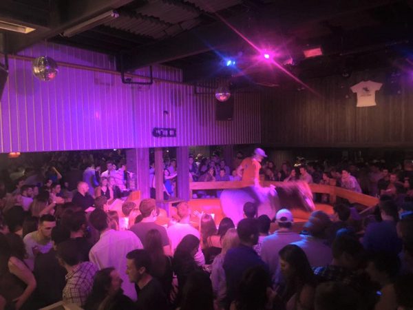guy riding a mechanical bull surrounded by people watching