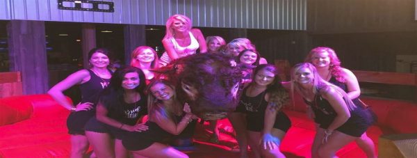 cowboy saloon employees taking a picture by a mechanical bull